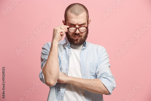 Suspiciont. Doubtful man with thoughtful expression making choice against pink background photo
