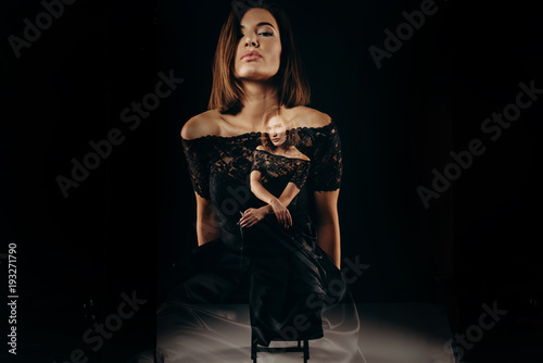 Double exposhure. Artistic portrait of a young beautiful woman. Fashion theater of fashionable girl in dark dress on big black background. Studio. Low Key. Fashion. Beauty.
