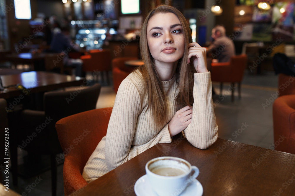 Young beautiful girl with a cup of drinks at a coffee house
