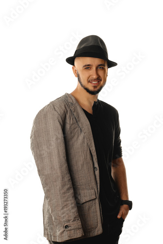 Happy young unshaved man in hat and jacket smiling on camera