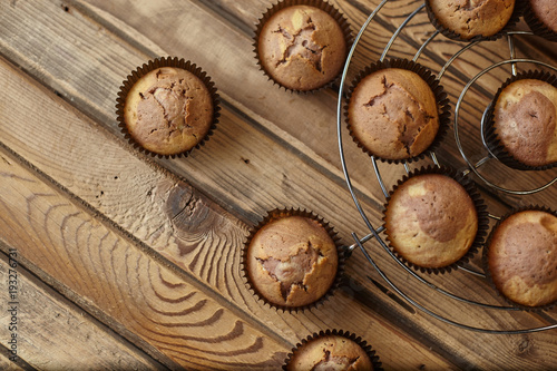 Cupcakes in brown paper form on an iron stand on a wooden table