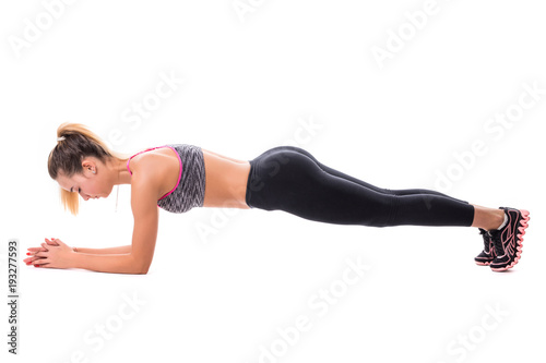 Concentrated beautiful fitness girl in sportwear exercising doing plank over white background