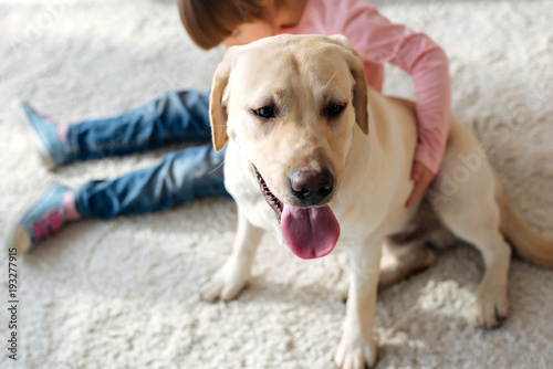 Preadolescent girl with down syndrome hugging Labrador retriever dog