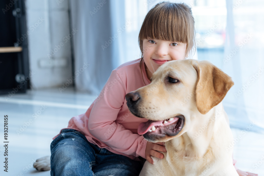 Kid with down syndrome and Labrador retriever resting on the floor
