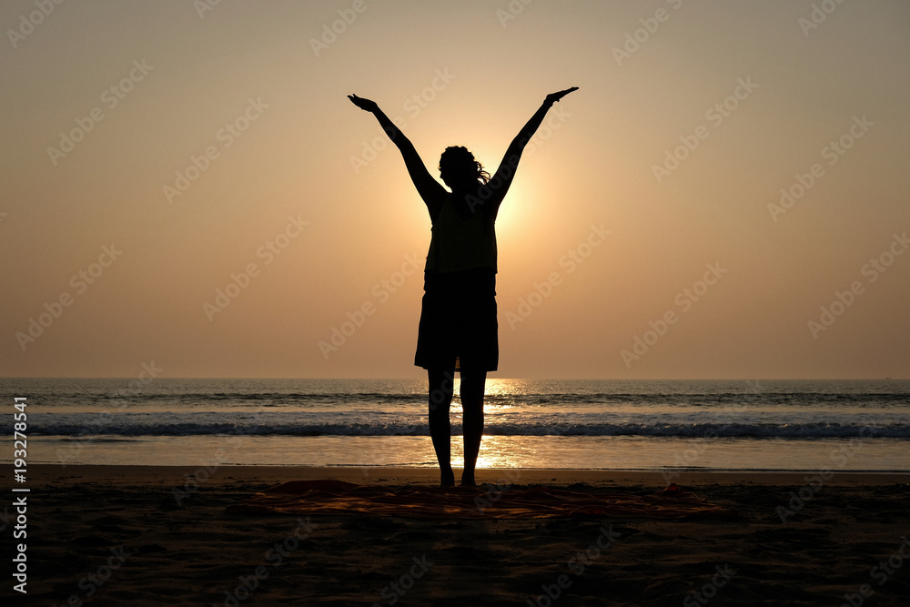 Woman's silhouette making fun on the beach at sunseteven