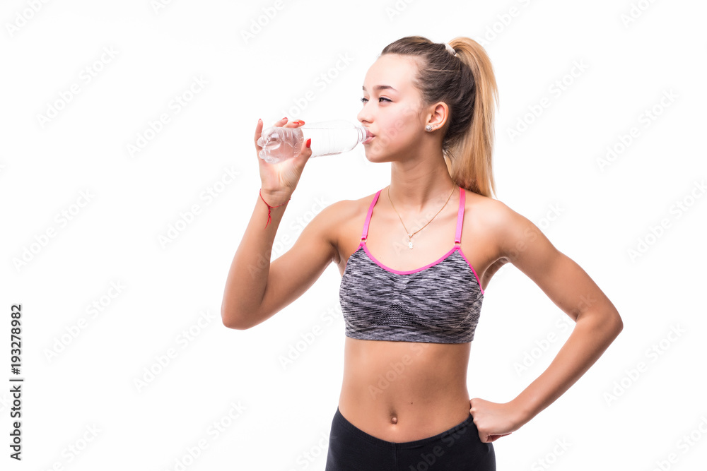 Young woman in fitness wear drinking iolated over white Young woman in fitness wear drinking iolated over white