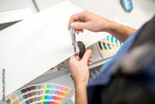 Slika na platnu Man measuring thickness of the paper sheet with micrometer at the printing plant