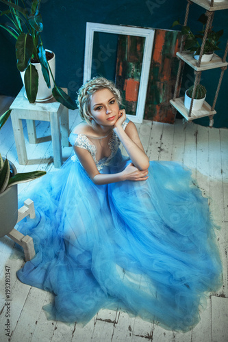 Beautiful model wearing light blue dress is posing in a studio 