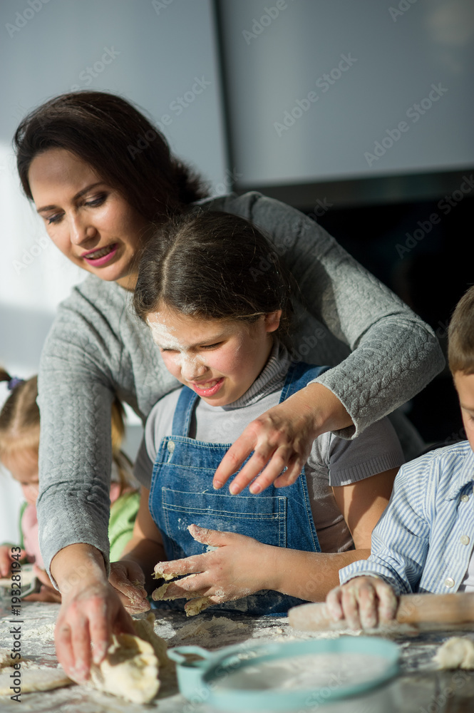 Mother and three children prepare something from the dough.