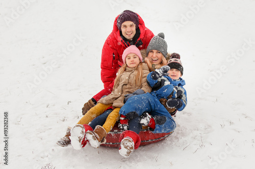 Picture of happy parents with daughter and son sitting on tubing in winter photo