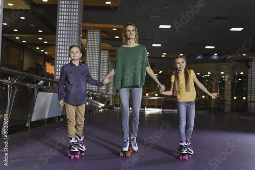 mother and kids holding hands while skating together on roller rink