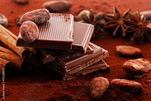Broken dark chocolate, cocoa powder and coffee beans on a wooden table
