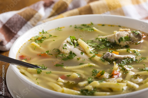 Chicken noodle soup with spoon and herbs