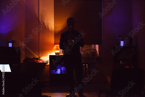 Man playing on saxophone in dark room