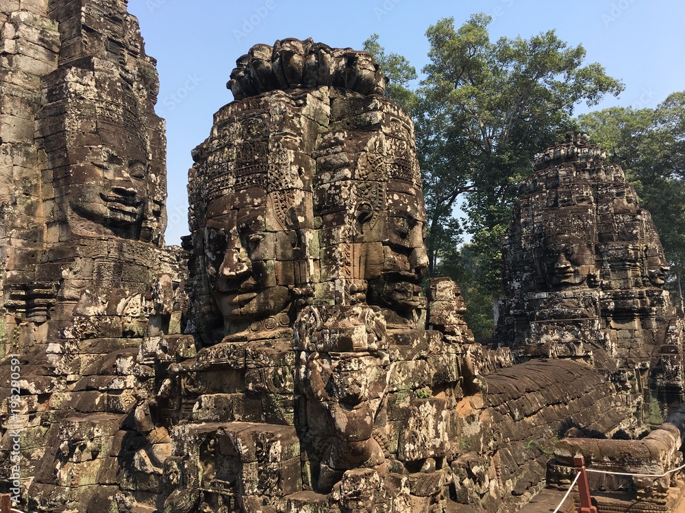 Angkor Wat in Siem Reap, Cambodia. Stone faces carved in the ancient ruins of Bayon Khmer Temple Angkor Wat in Siem Reap, Cambodia. Stone faces carved in the ancient ruins of Bayon Khmer Temple