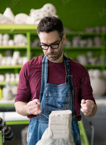 Ceramist Dressed in an Apron Working with Raw Clay in Bright Ceramic Workshop. photo