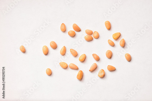 Foto Useful pine nuts lie on a white paper background