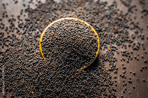 Tableau sur toile Close up of mustard seeds/Rai or brown mustard seeds in a small plate on a wooden surface in dark Gothic colors
