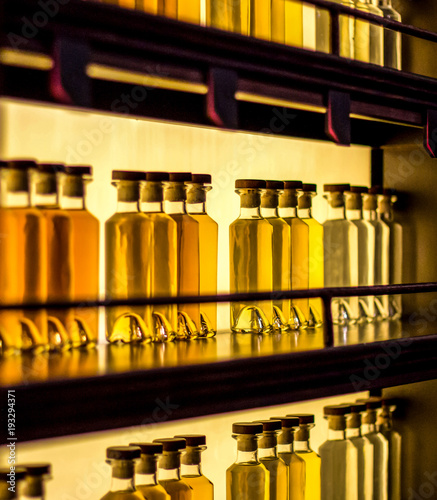 Glass bottles with yellow liquid on wooden shelves © solidmaks