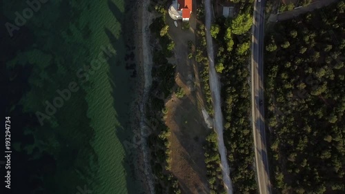 Flying over the waterfront road among green trees leading to the neighbourhood on the coast. Trikorfo Beach, Greece photo