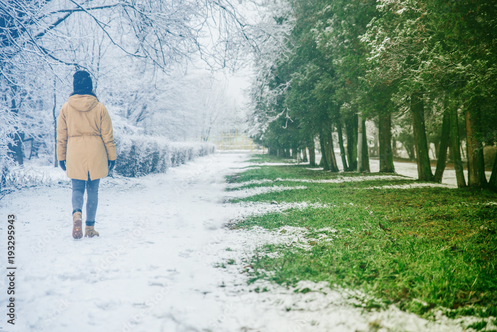 woman walk by park where winter meet spring woman walk by park where winter meet spring