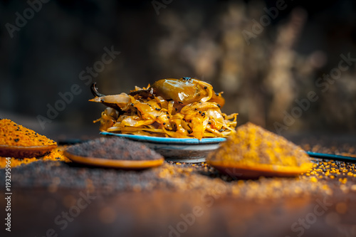 Popular Indian cabbage pickle with all spices and other vegetable i.e chili on a wooden surface in dark Gothic colors. photo