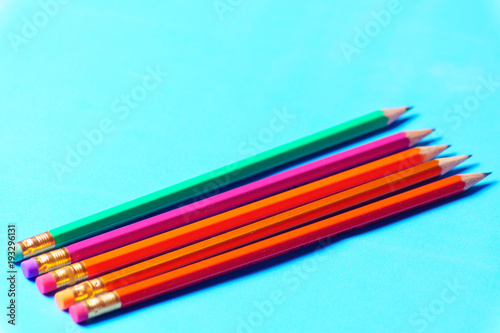 colored pencils in a row on green background.