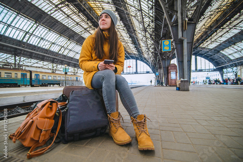 young woman sit at railway station on her bags. Waiting for trai photo