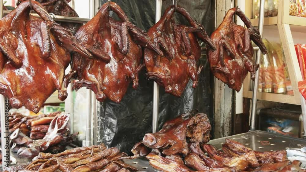 pan of peking duck hanging in a restaurant's window in chinatown, bangkok