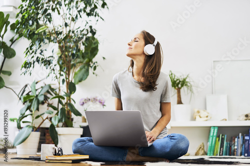 Young woman listening to music on laptop while sitting at home photo