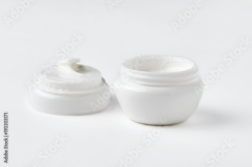 Open jar with face cream on a white background