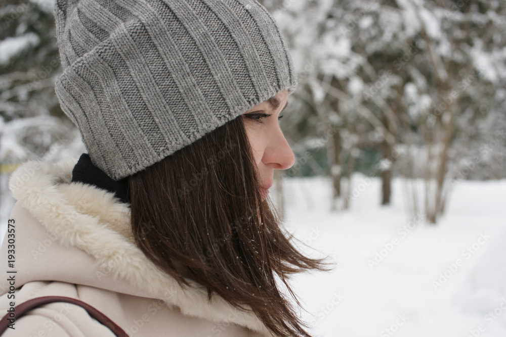 Beautiful brunette in winter in hat on the background of the forest Beautiful brunette in winter in hat on the background of the forest
