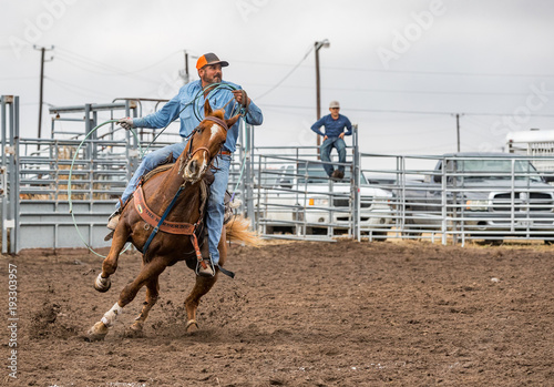 Cowboy riding in a ranch rodeo with lasso during a roping competition
