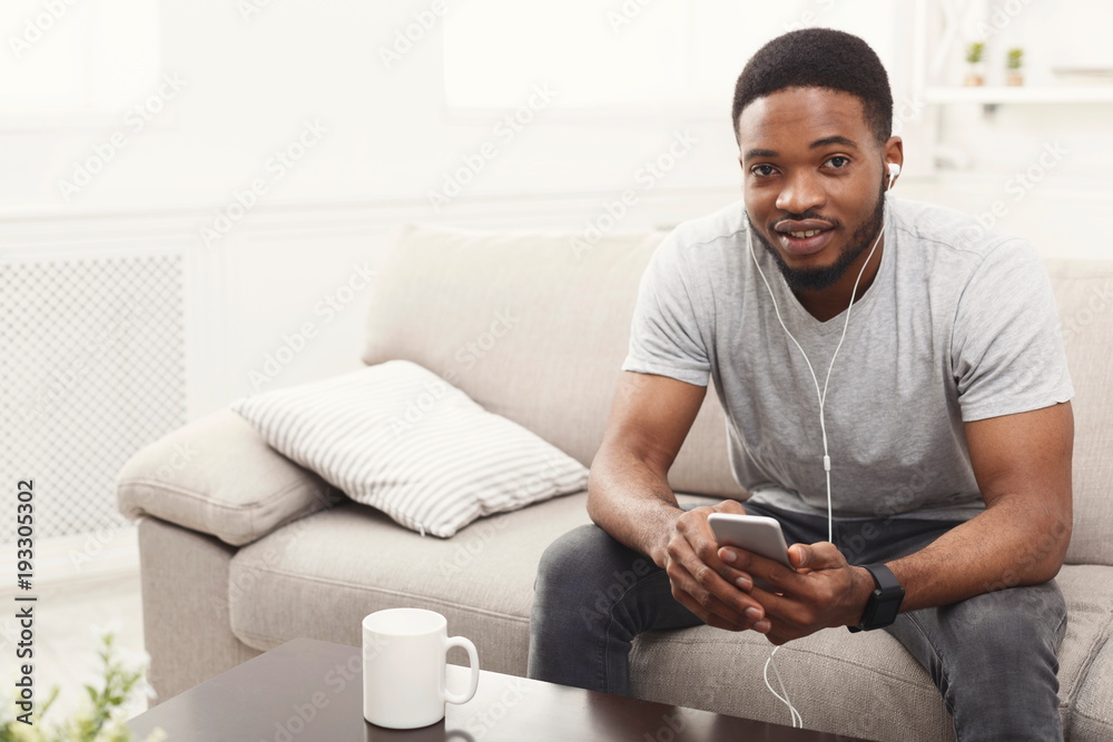Young african-american man in earphones with mobile phone