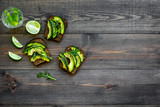 Have a bite with healthy snacks. Avocado toast on dark wooden background top view copy space