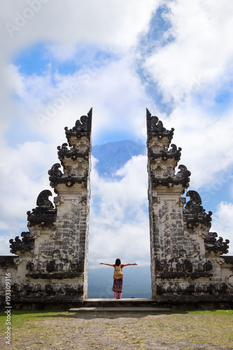 Young women watching view of the Agung volcano near sculpture gate in Pura Penataran Agung Lempuyang in Bali, Indonesia