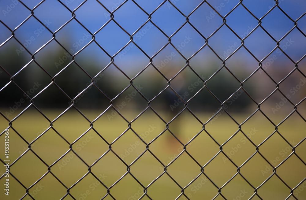 Wire metallic mesh fence around a soccer field. Blurred background, close up view with details. Wire metallic mesh fence around a soccer field. Blurred background, close up view with details.