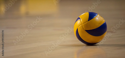 Fotografie Volleyball ball on blurred wooden parquet background