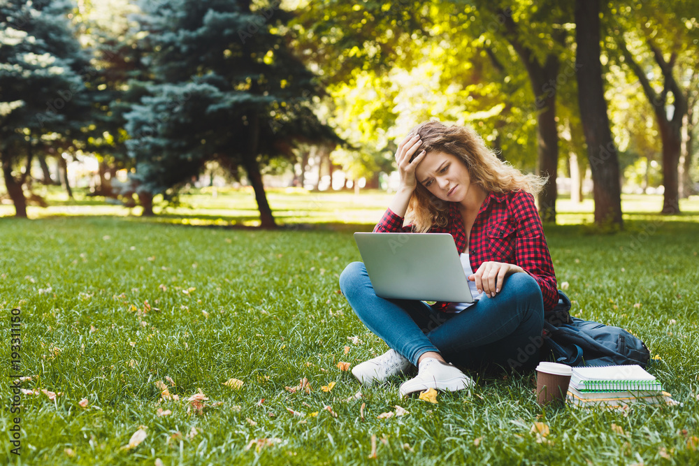 Desparate young woman using a laptop outdoors Desparate young woman using a laptop outdoors