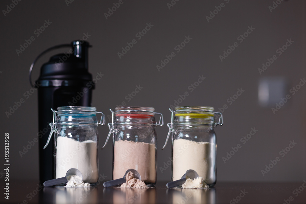 Composition with protein shake, powder and dumbbell on table Composition with protein shake, powder and dumbbell on table