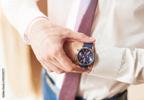 A man in a white shirt adjusts his watch