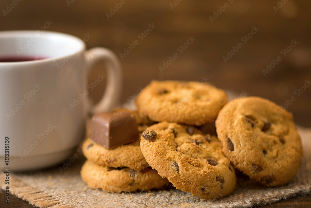 White cup of tea and cookies on dark wooden background
