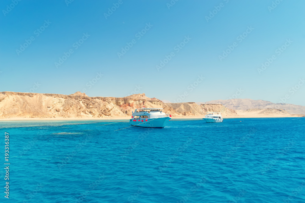 yacht in the sea, against a background of a deserted shore, waves, blue sky