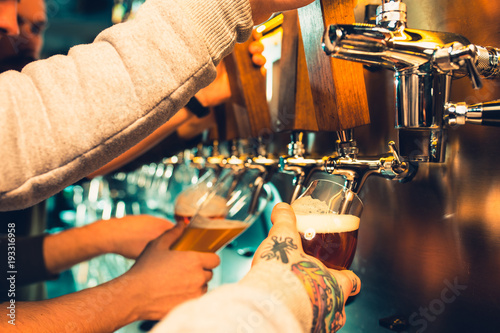 Canvas-taulu Hand of bartender pouring a large lager beer in tap.