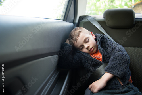 adorable sleeping child on the back seat of the car with safety belt