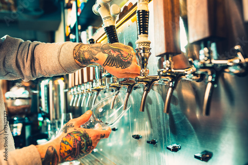 Hand of bartender pouring a large lager beer in tap.