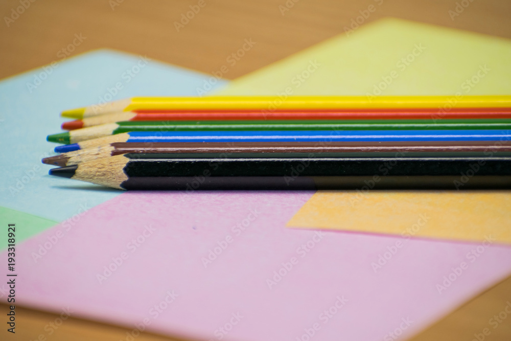 Close up stack colour pencils on papper and wooden background Close up stack colour pencils on papper and wooden background