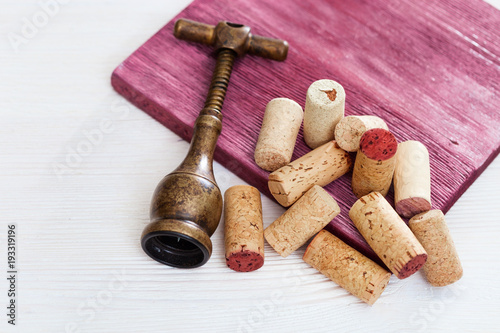 Vintage corkscrew and heap used wine corks on  wooden background. Spin and stopper corks from red wine. Copy space. Top view.