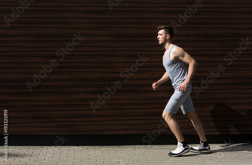Young man running in city copy space