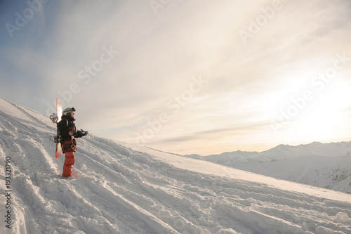 Young snowboarder standing on the mountain snow